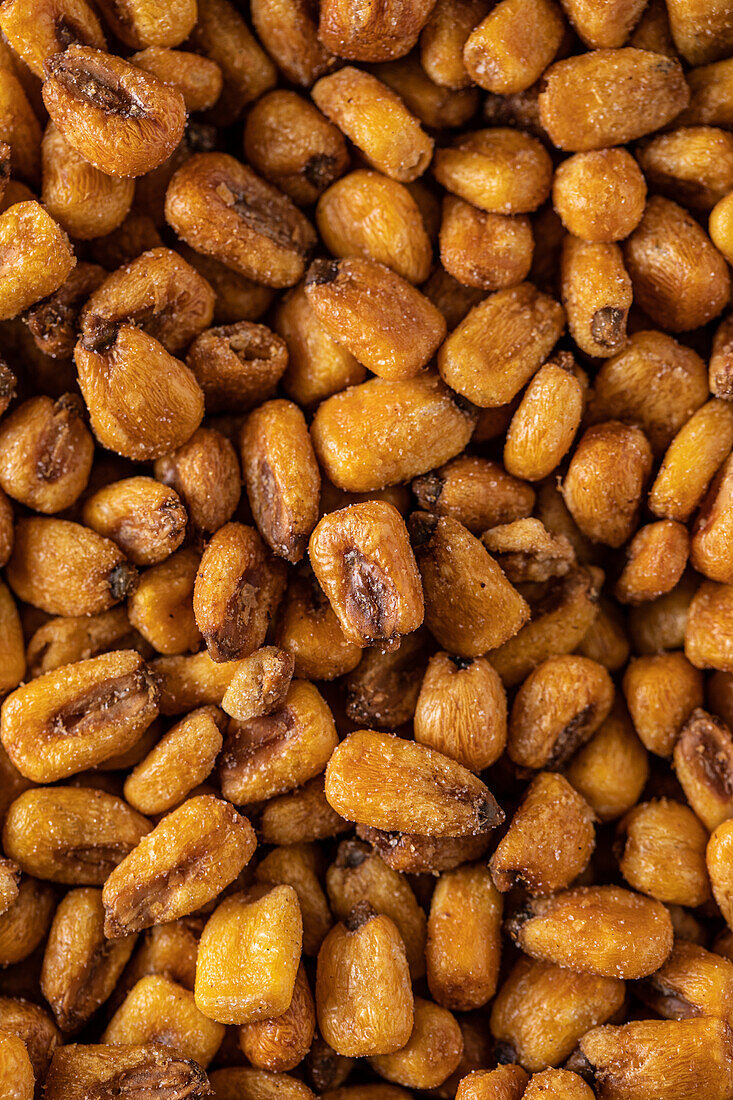Full frame top view of heap of crispy roasted corn kernels scattered on surface