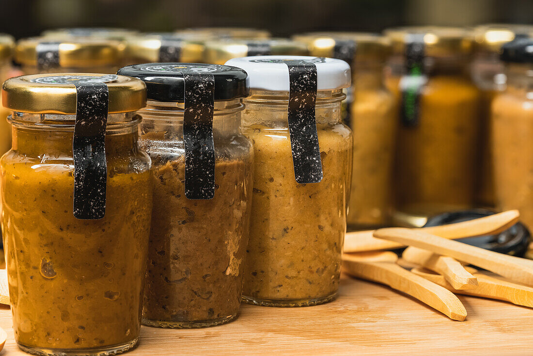 Nahaufnahme vieler geschlossener Glasflaschen mit frischer gelber hausgemachter Gemüsemischung auf dem Tisch