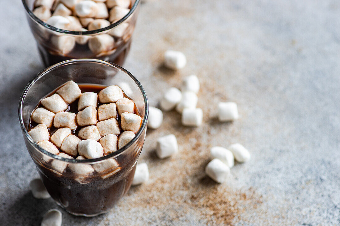Hot chocolate with mini marshmallow in the glass on concrete background