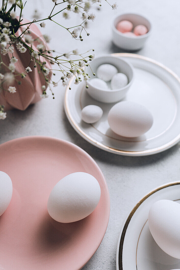 From above still life of beautiful painted Easter eggs over white table background near cute flowers