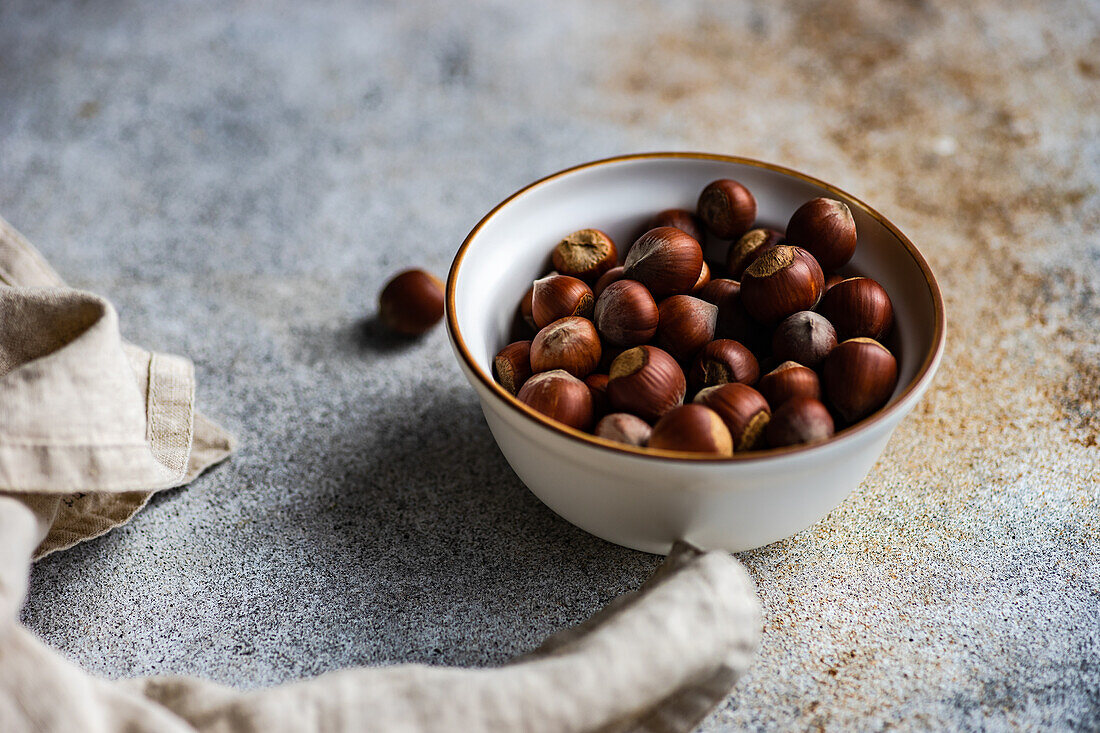 From above bowl full of tasty fresh hazelnut on concrete background