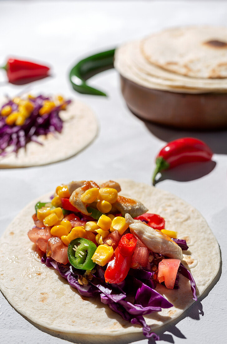 Homemade Mexican Tacos with fresh vegetables and chicken with strong light on white background. Healthy food. Typical Mexican