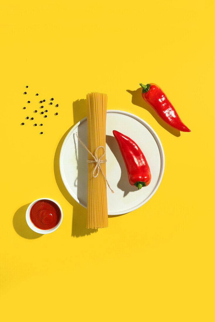 Von oben appetitlich frische trockene Spaghetti mit roter Soße und Gewürzdip rote Paprika auf gelbem Hintergrund