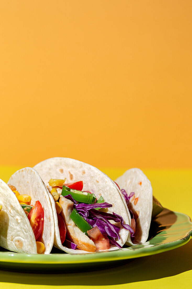 Homemade Mexican Tacos with fresh vegetables and chicken with strong light on yellow background. Healthy food. Typical Mexican