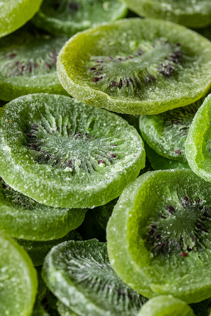 Full frame of pile of sliced sweet green dry kiwi with sugar placed on surface