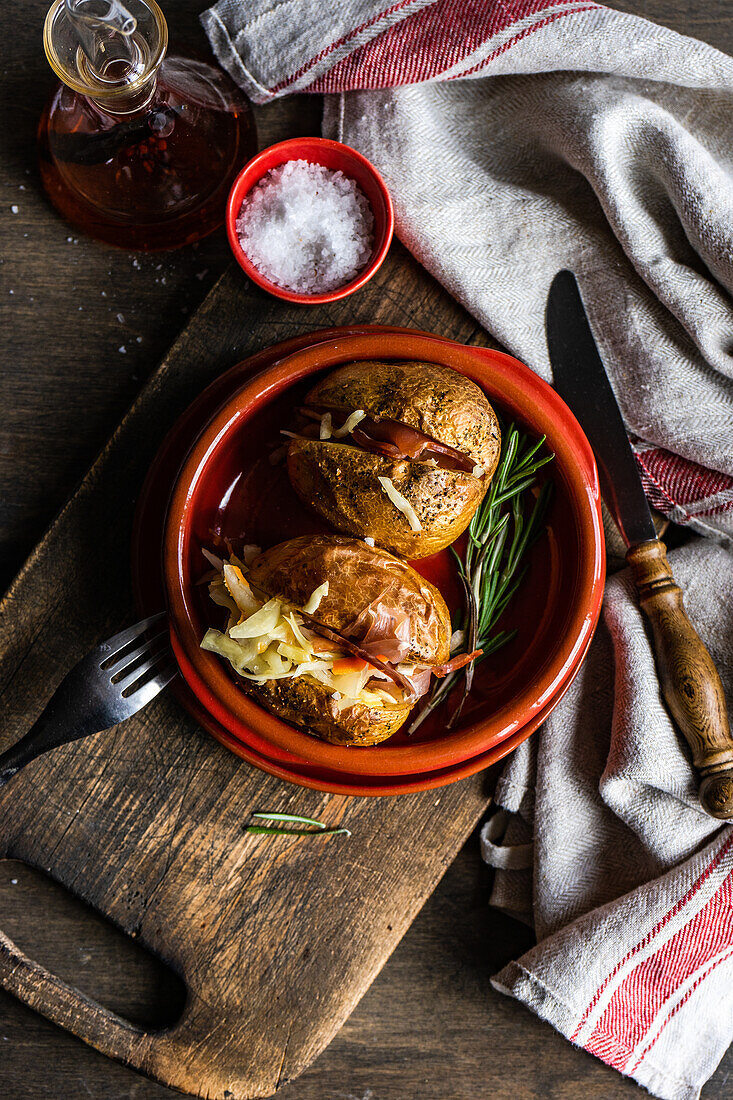 From above baked potato in jacket with bacon and cabbage served in the a terracotta ceramic oven bowl