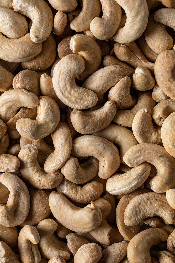 Full frame top view of huge amount of raw tasty cashews placed on smooth surface