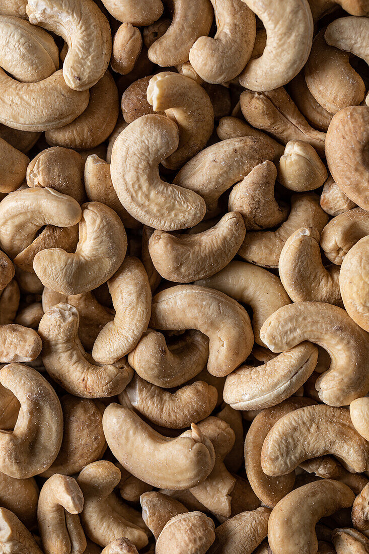 Vollbildansicht von oben einer großen Menge roher, schmackhafter Cashews auf glatter Oberfläche