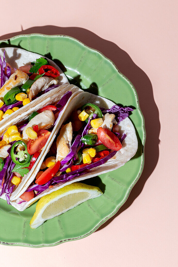 Hausgemachte mexikanische Tacos mit frischem Gemüse und Huhn mit starkem Licht auf rosa Hintergrund. Gesundes Essen. Typisch mexikanisch