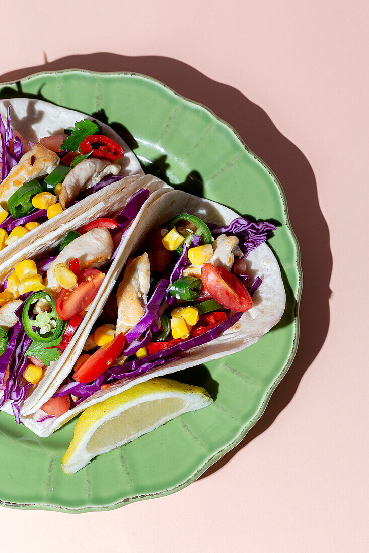 Homemade Mexican Tacos with fresh vegetables and chicken with strong light on pink background. Healthy food. Typical Mexican