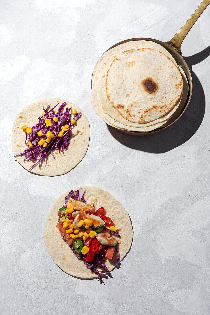 Homemade Mexican Tacos with fresh vegetables and chicken with strong light on white background. Healthy food. Typical Mexican