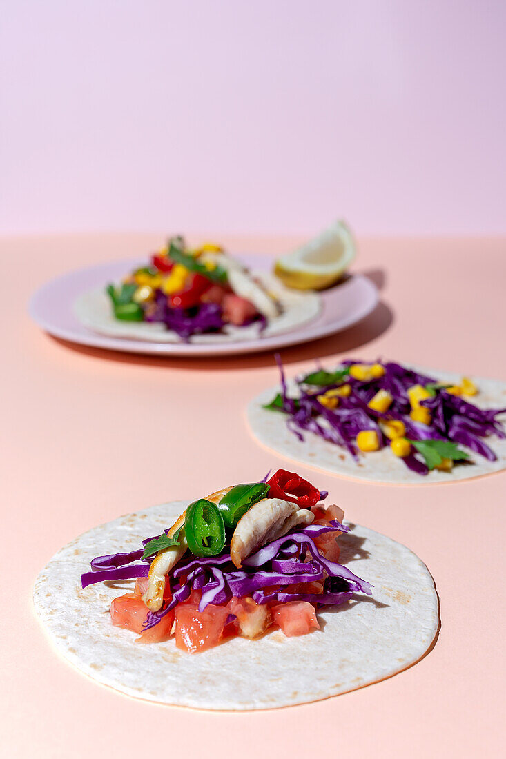 Homemade Mexican Tacos with fresh vegetables and chicken with strong light on PINK background. Healthy food. Typical Mexican