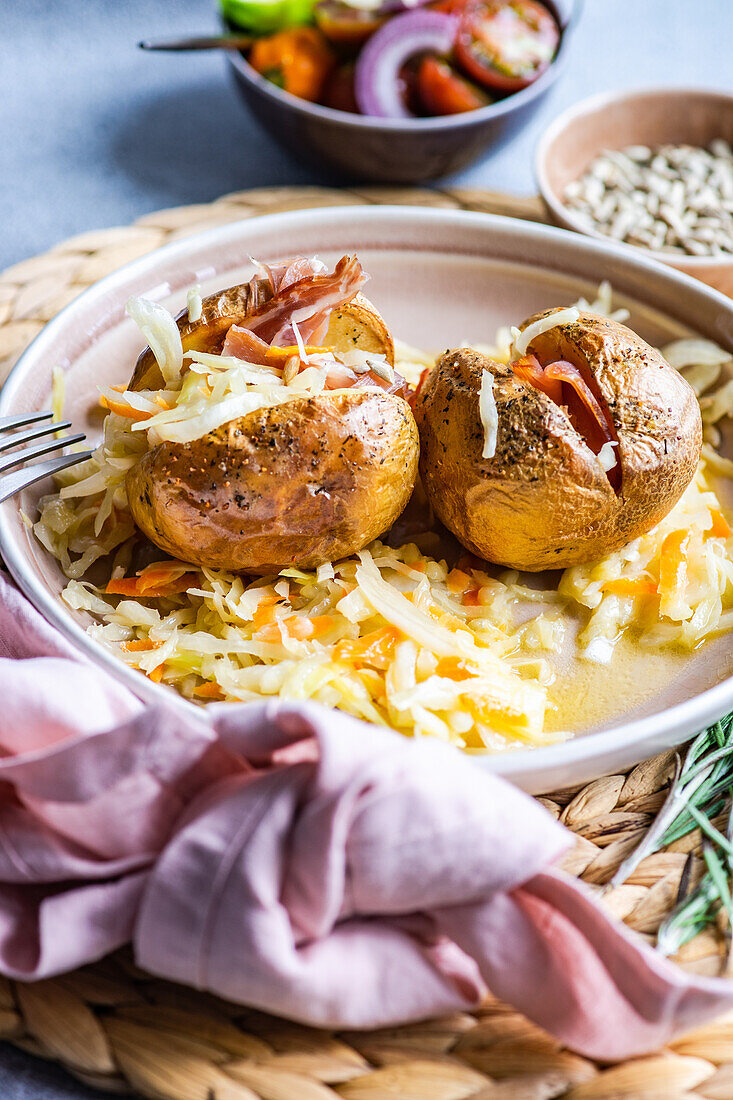 Gebackene Kartoffel im Päckchen mit Speck und Kohl auf einem Teller von oben