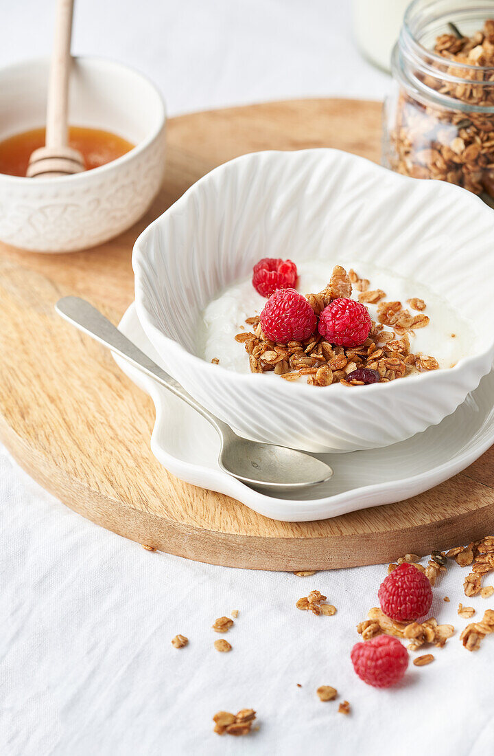 Tasty granola with sweet honey and fresh dairy product served for breakfast on wooden board