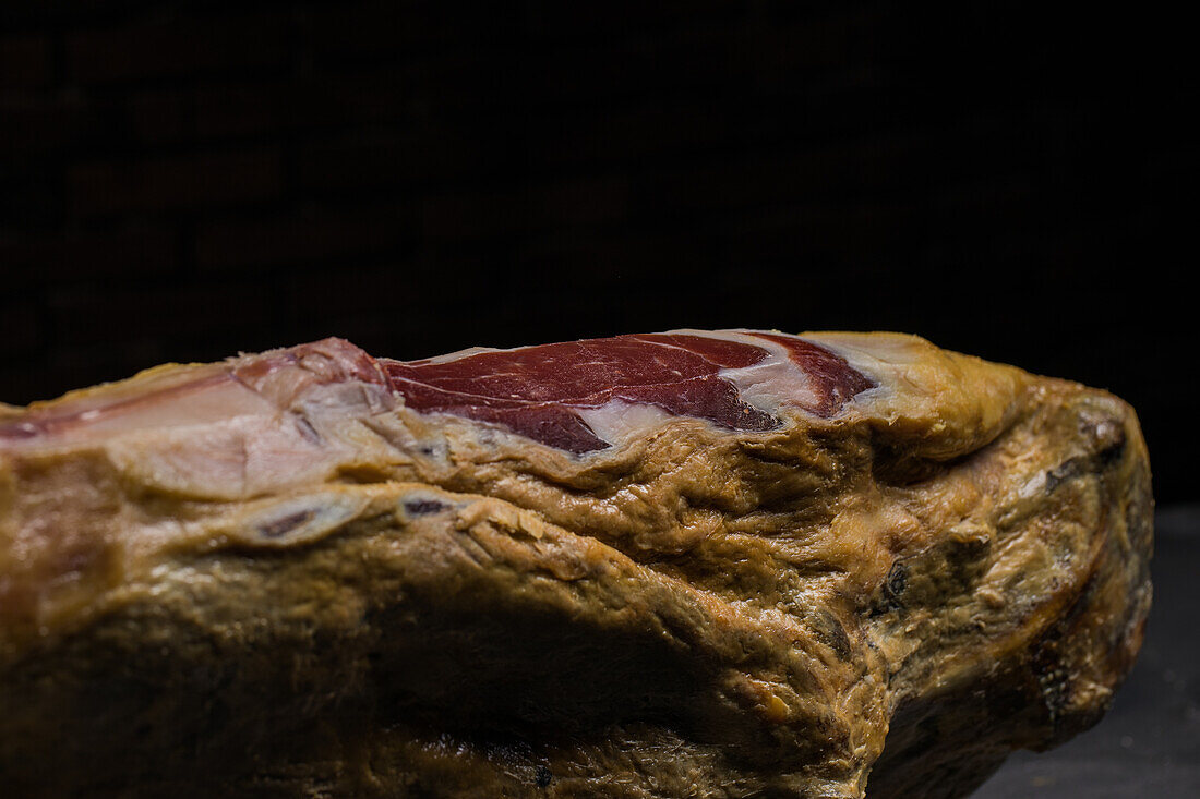 Delicious dry cured Spanish pork leg on wooden holder on gray surface