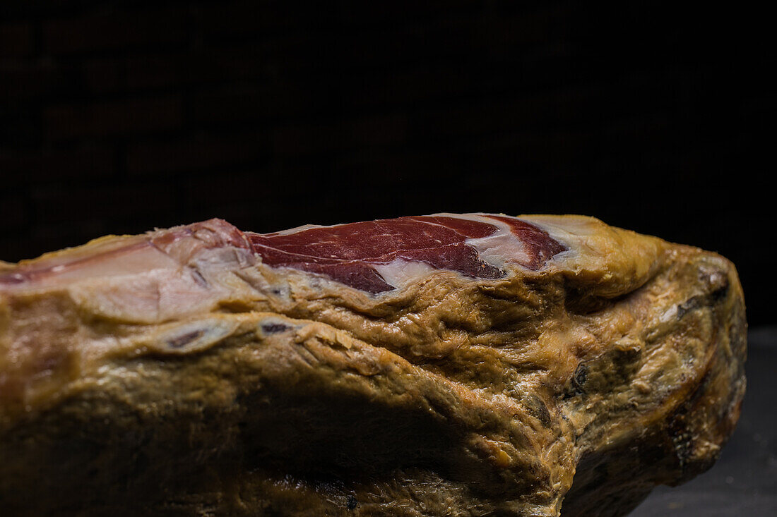 Leckere trocken gepökelte spanische Schweinekeule auf Holzständer auf grauem Untergrund