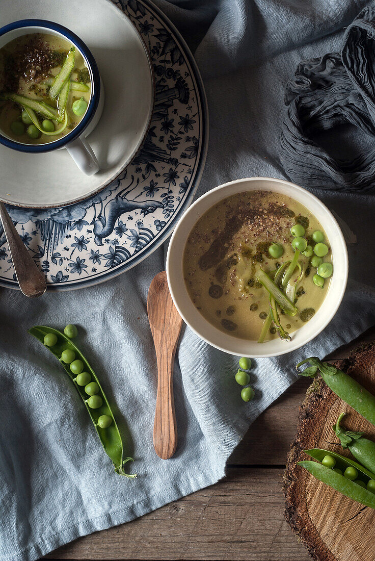Closeup of served bowls with green pea and coconut cream soup on table