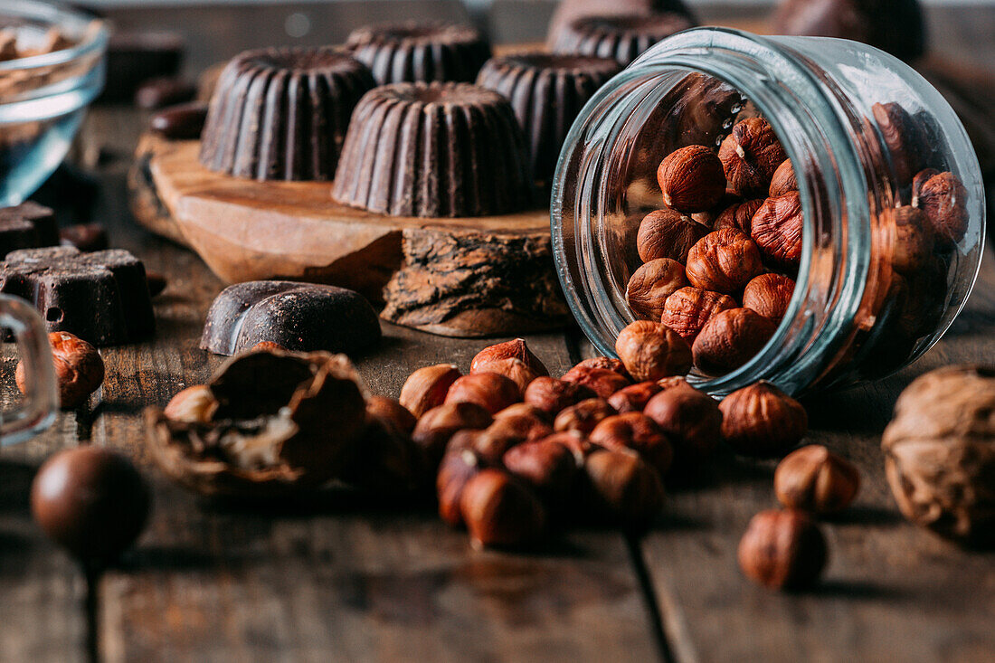 Various handmade chocolates with nuts arranged on wooden table with peanut butter and cinnamon sticks