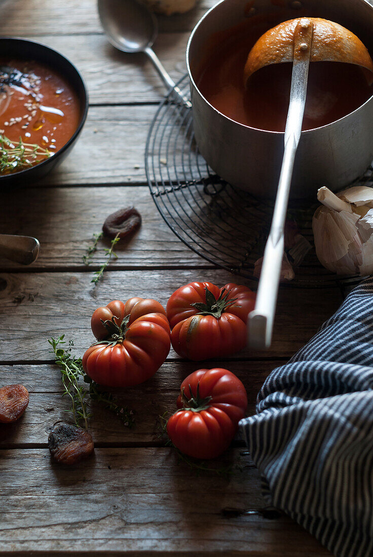 Flat lay of bowls with creamy tomato soup garnished with seeds and served on table with tomatoes and dried apricots