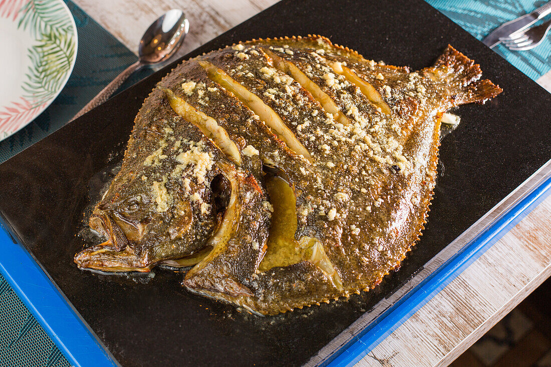 From above of savory turbot fish served on slate board on table in luxury restaurant