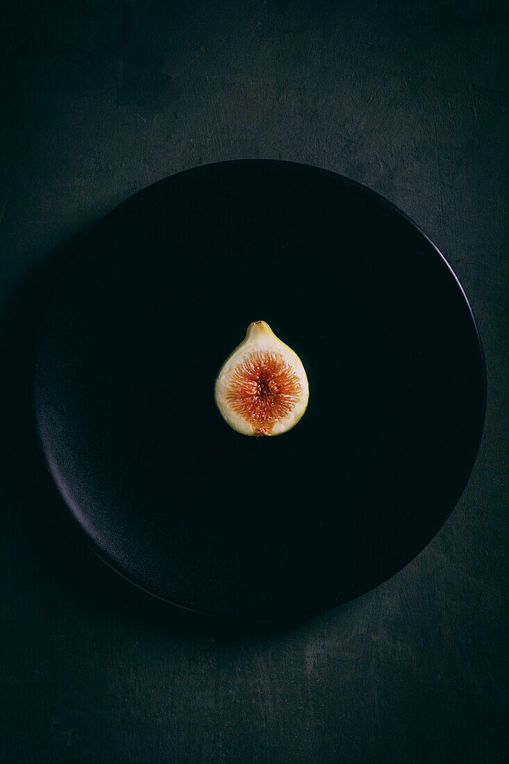 Top view of fresh sweet figs arranged on plate on dark background