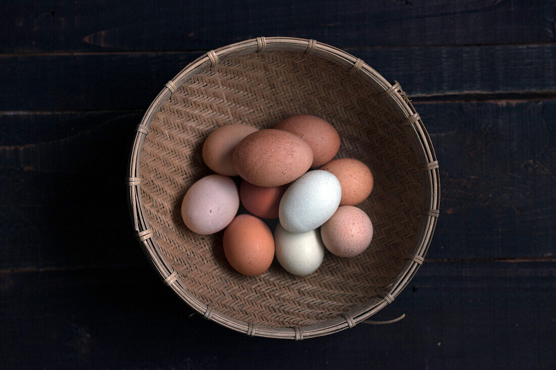 From above shot of wicker basket filled with brown and white eggs on table