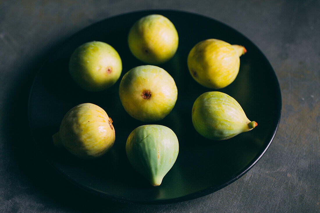 Top view of fresh sweet figs arranged on plate on dark background