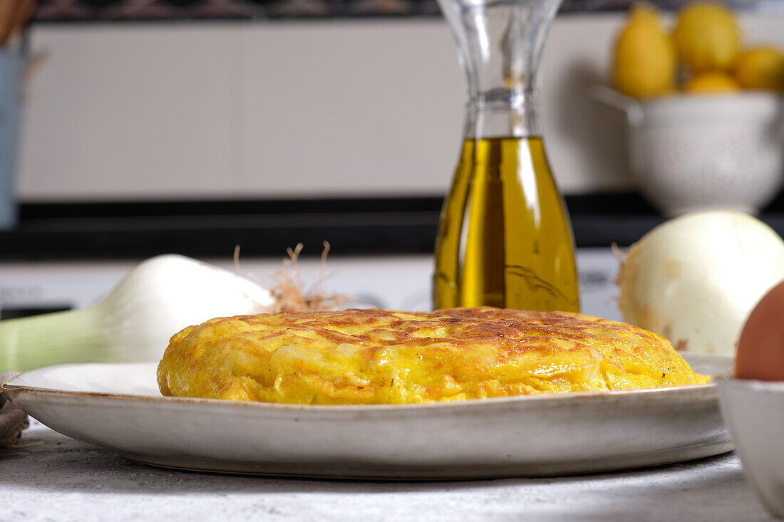 Appetizing traditional Spanish omelette placed on table with eggs and onion in domestic kitchen