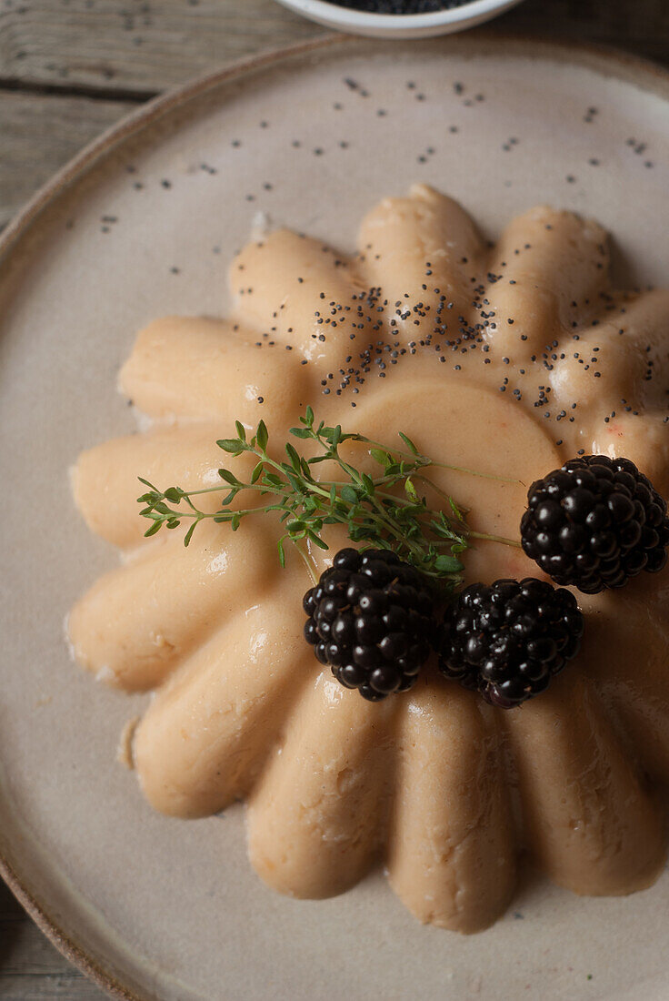 Closeup from above shot of tender peach panna cotta with blackberry and poppy seeds