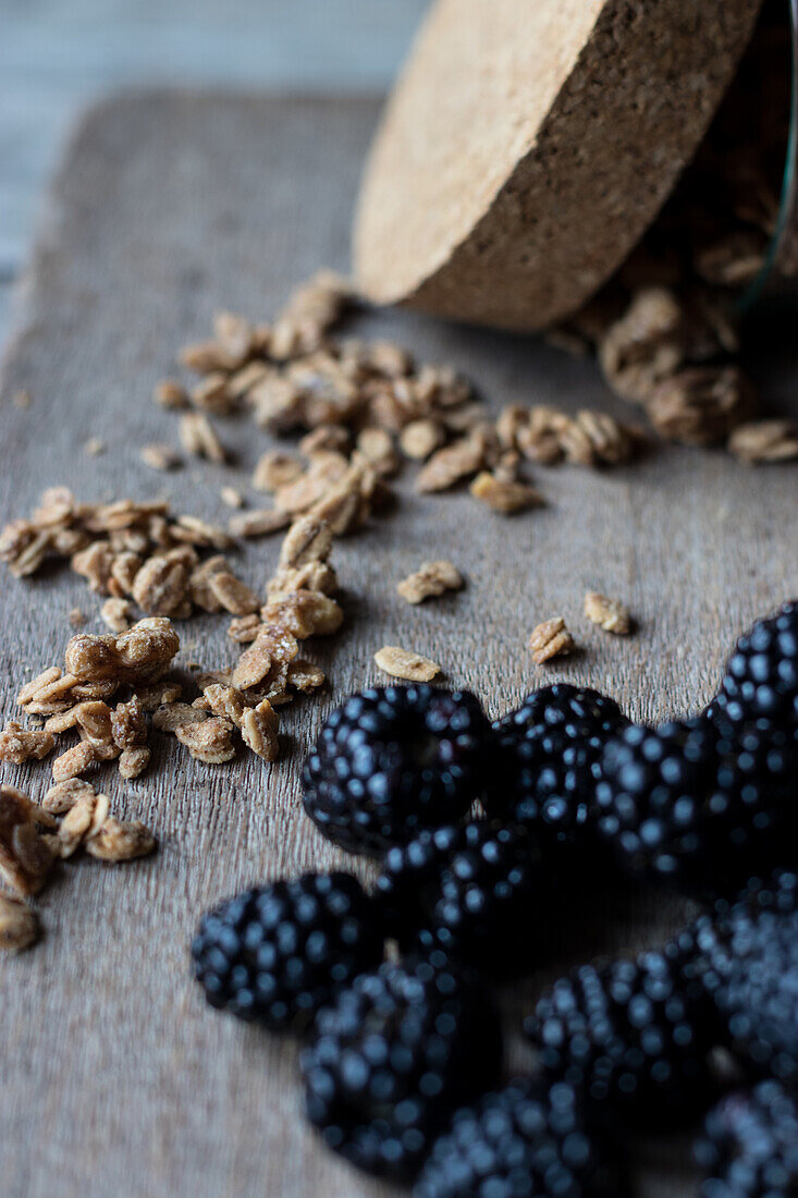 Nahaufnahme von oben von frischen reifen Blaubeeren und Walnussmüsli aus dem Glas auf einem hölzernen Schneidebrett