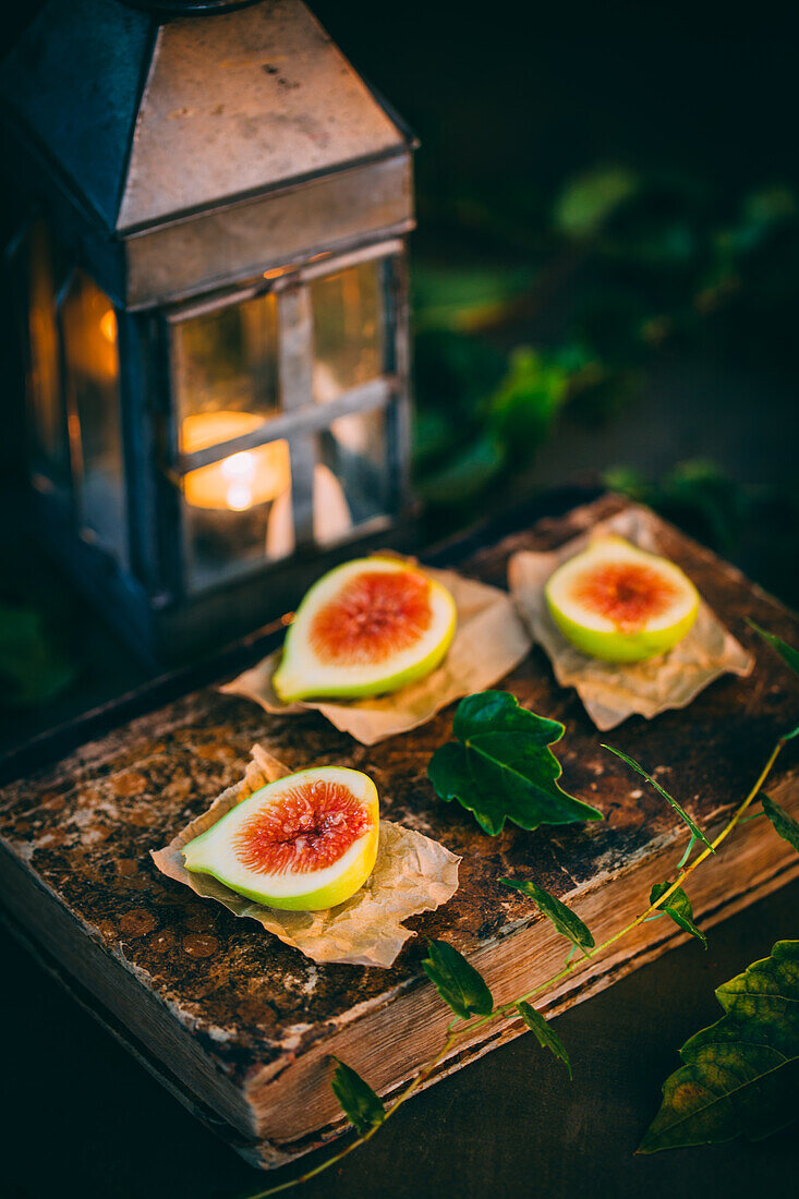 Top view of fresh sweet figs arranged on wooden chopping board with green leaves