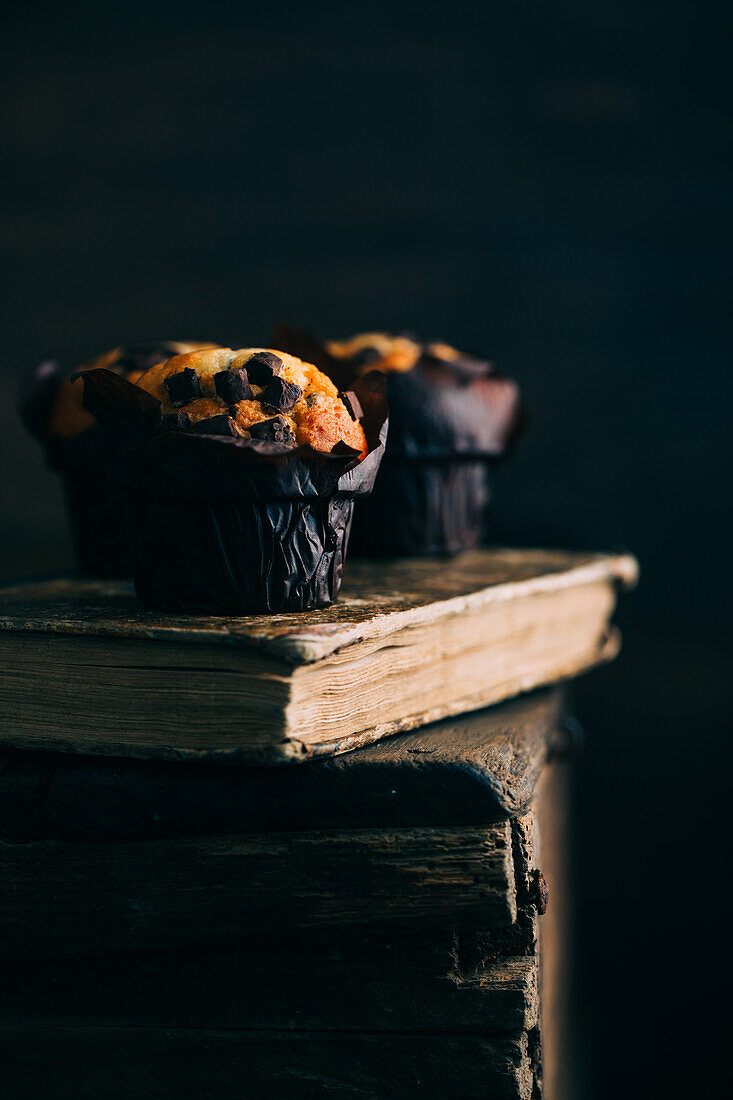 Chocolate muffins on an old book over a dark background