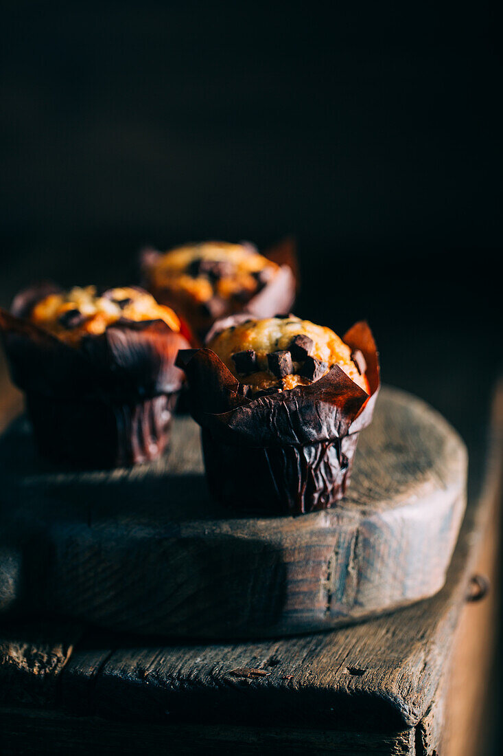 Leckere Muffins mit Schokoladenstückchen auf dunklem Holzhintergrund
