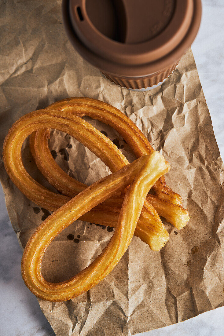 Frische, knusprige Churros und eine Tasse heißer Kaffee auf dem Tisch zum Frühstück