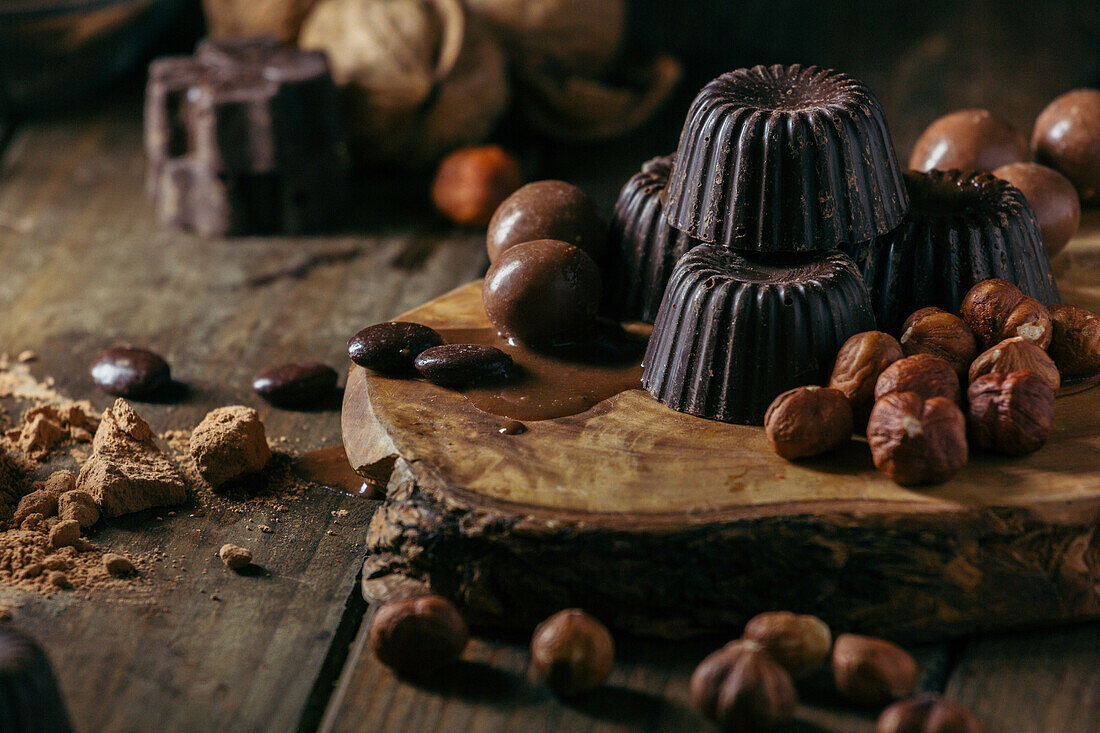 From above various handmade chocolates with nuts arranged on wooden table with peanut butter and cinnamon sticks