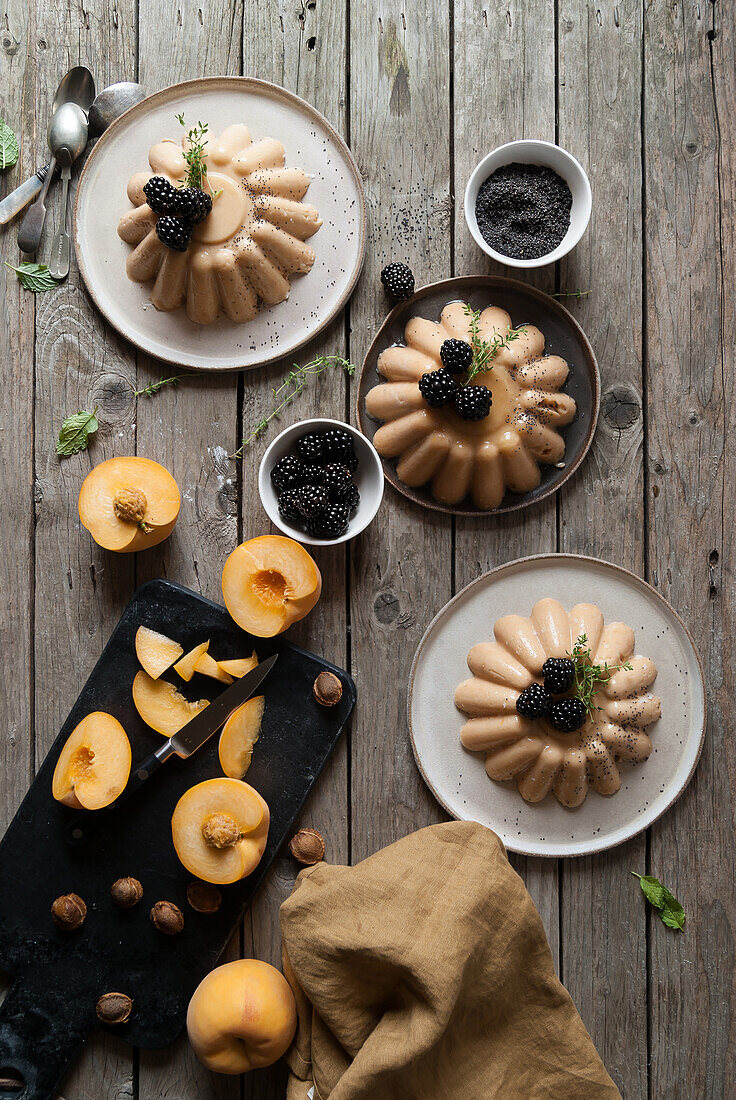 Flat lay of arranged served panna cotta with peach and poppy seeds on table with blackberry