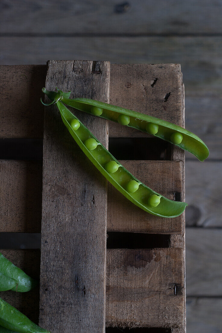 From above closeup view of fresh opened pod with shiny peas on wood