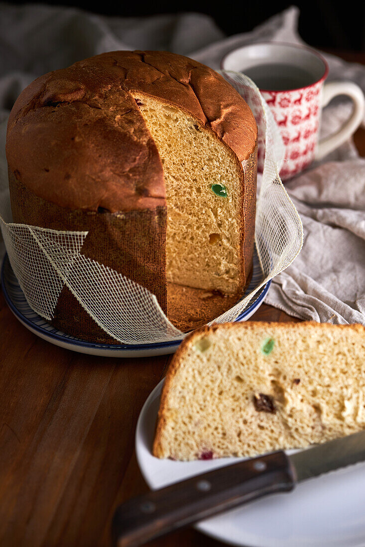 Hoher Winkel von in Scheiben geschnittenem, frisch gebackenem, handwerklich hergestelltem Weihnachts-Panettone-Kuchen auf einem Holztisch