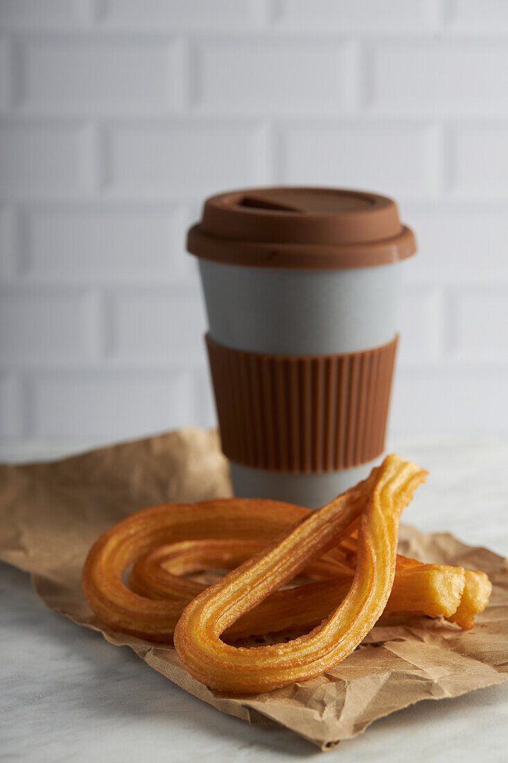 Fresh crispy churros and cup of hot coffee placed on table for breakfast