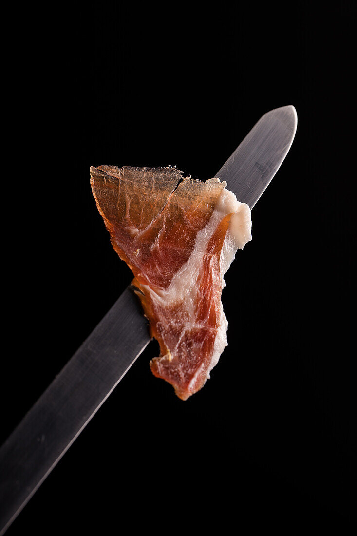 tasty thin dry cured Iberian jamon slice with pleasant aroma and torn edges
