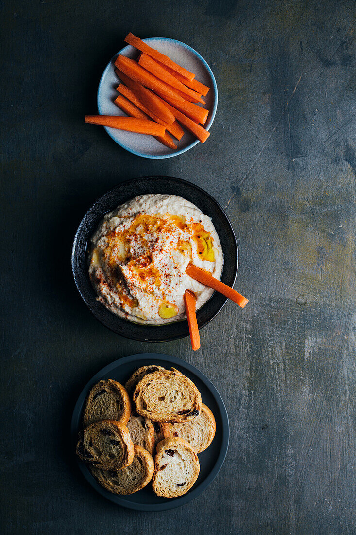 Leckerer Hummus mit Paprika, Olivenöl und etwas Brot zum Dippen