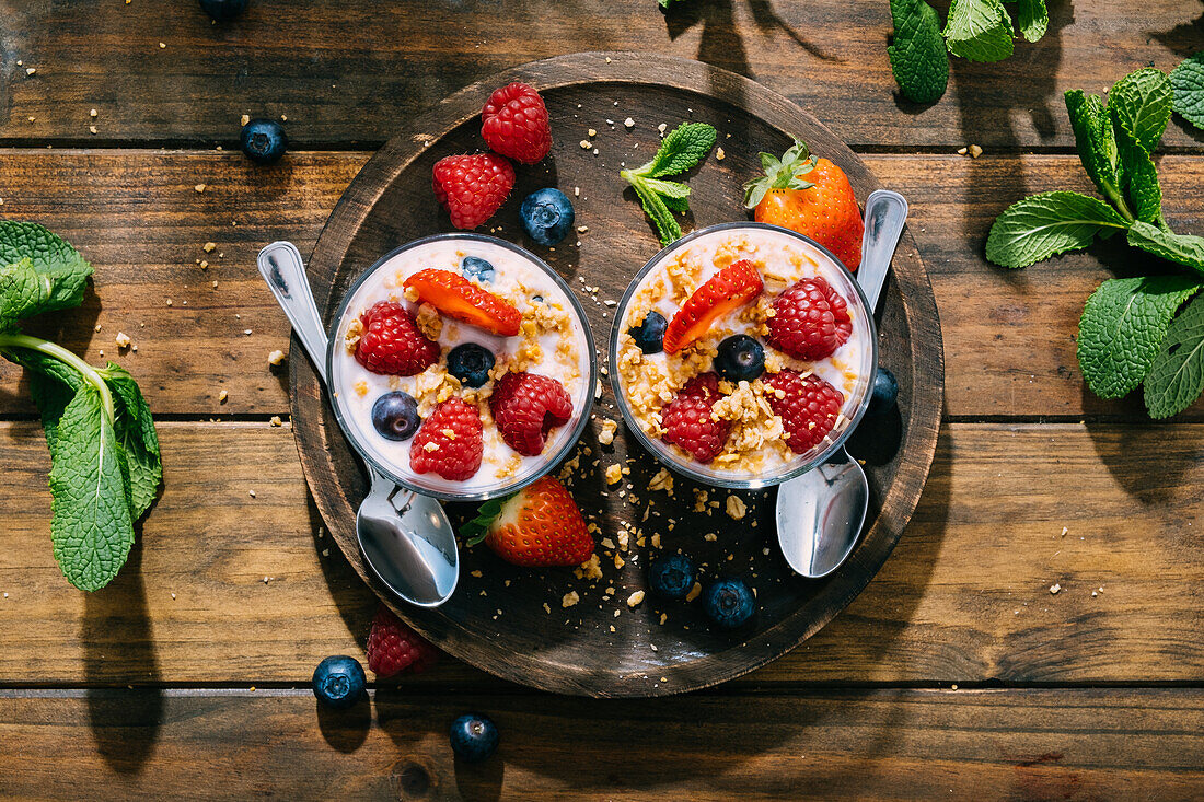 From above top view of delicious homemade yogurt with strawberries, berries and cereals on wooden table background