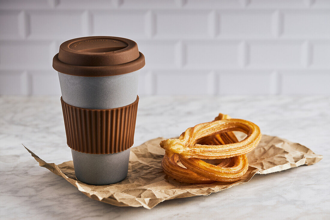 Fresh crispy churros and cup of hot coffee placed on table for breakfast