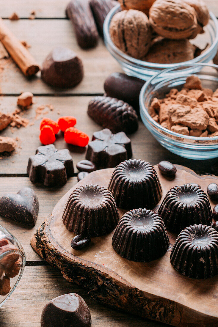 Various handmade chocolates with nuts arranged on wooden table with cinnamon sticks