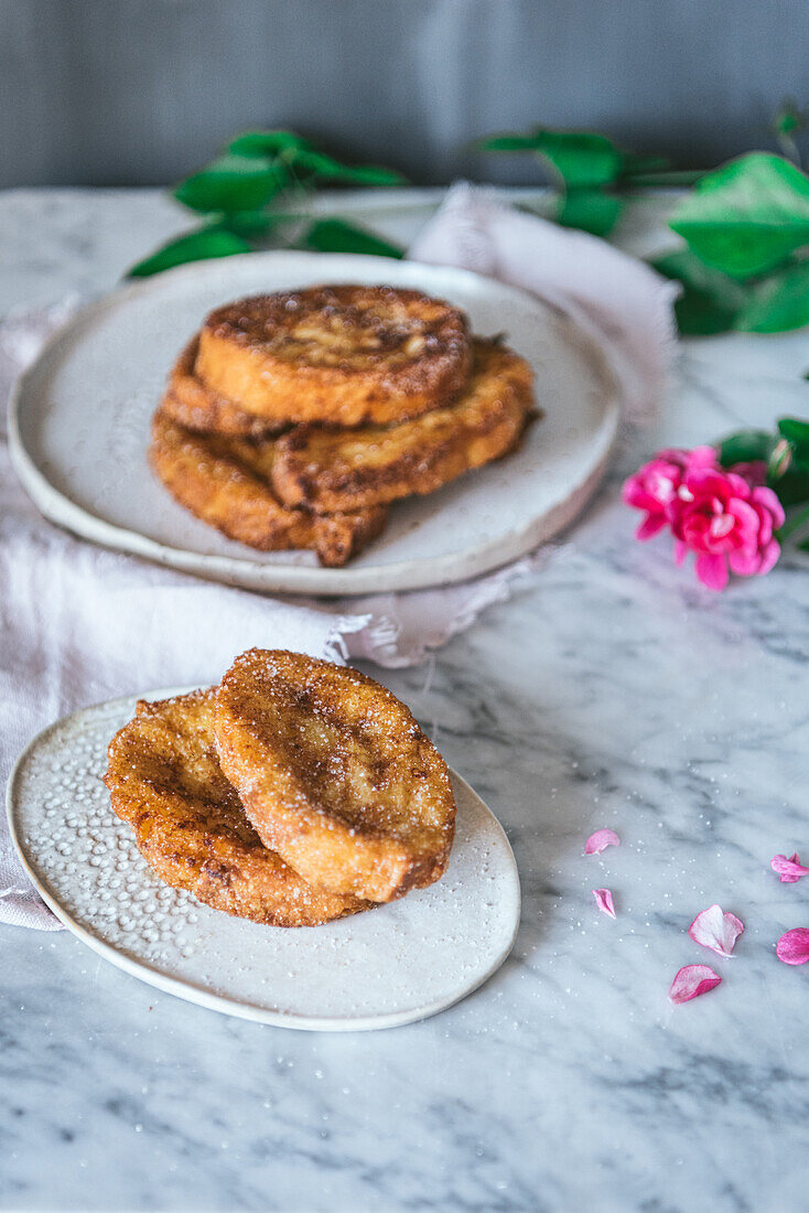 From above homemade traditional easter Spanish French toast dessert served on plate near a rose flower on marple background