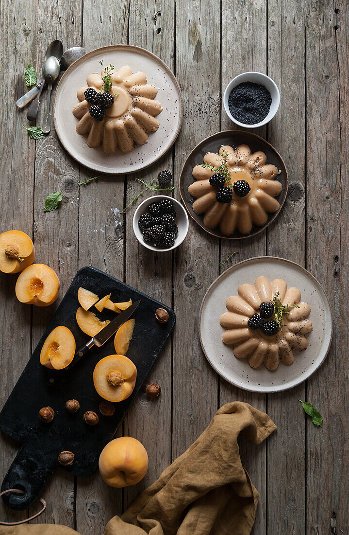 Flat lay of arranged served panna cotta with peach and poppy seeds on table with blackberry