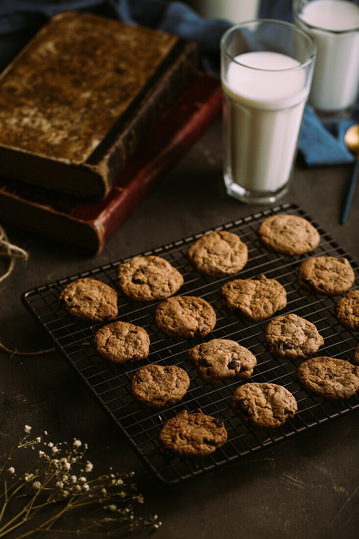 Homemade chocolate chips cookies on cooling rack with a glass of milk