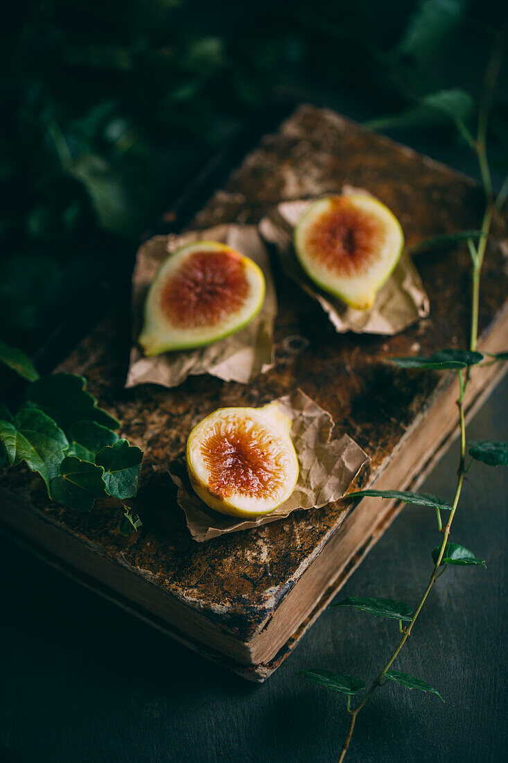 Top view of fresh sweet figs arranged on wooden chopping board with green leaves