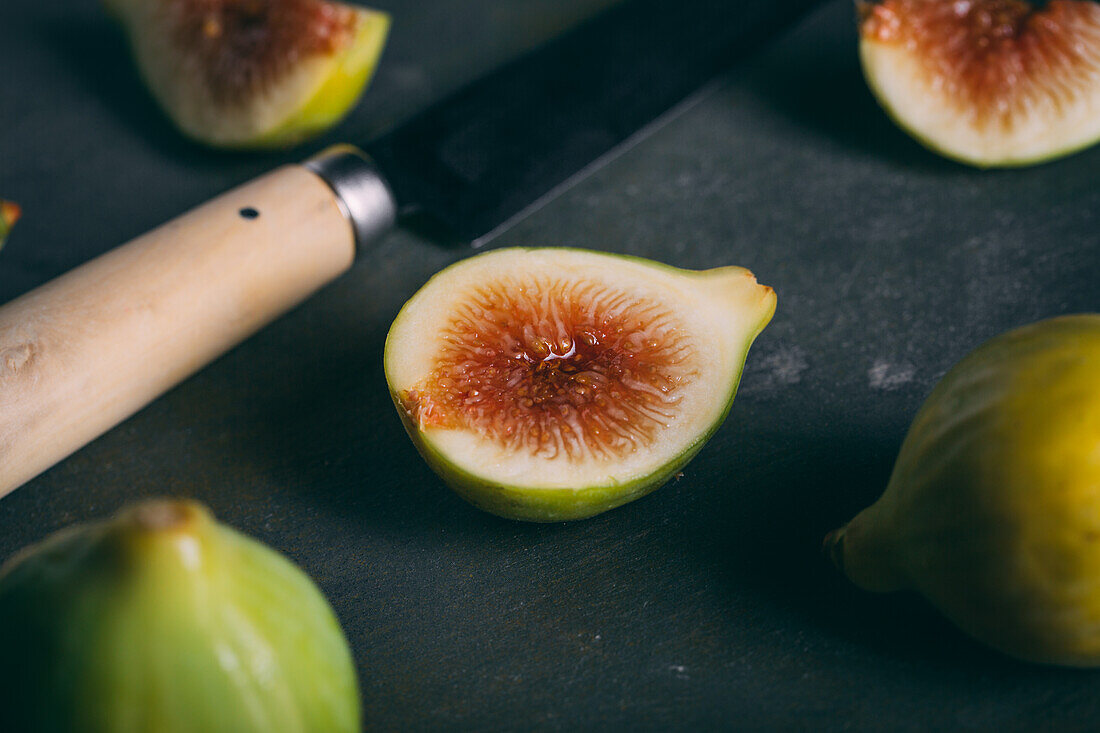Closeup of fresh sweet figs arranged with knife on dark background