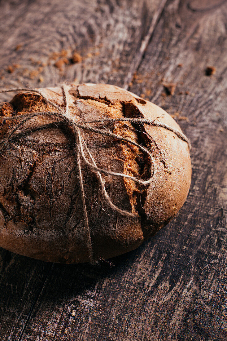 From above of delicious freshly baked bread placed on aged cutting board on wooden table in kitchen